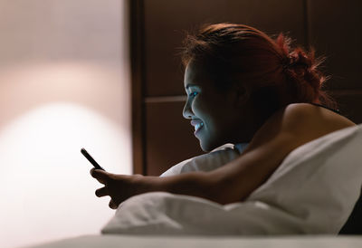 Side view of girl using mobile phone at home