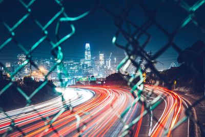 Light trails on city street against sky at night