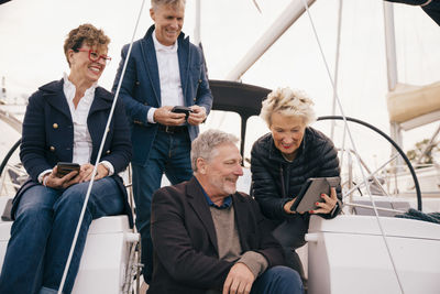 Senior couple using digital tablet while traveling with friends in yacht