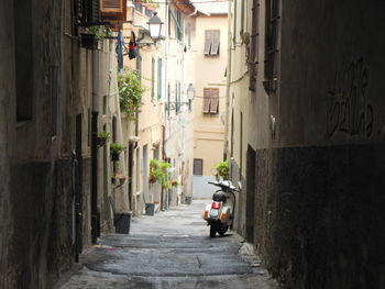 Motor scooter parked in alley amidst buildings