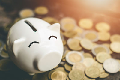 Close-up of coins and piggy bank on table