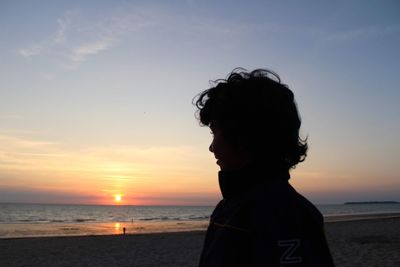 Portrait of man on beach against sky during sunset