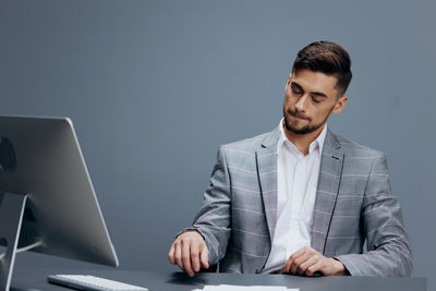 Portrait of young man using laptop while sitting at desk in office