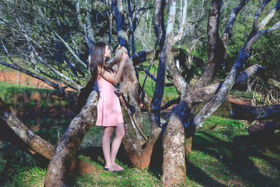 Woman standing by tree in forest