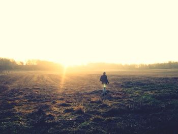 Silhouette of woman standing on field at sunset