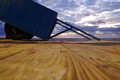 Surface level of metallic structure on beach against sky