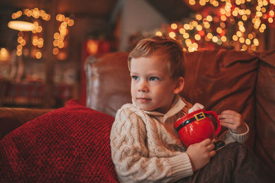 Portrait candid happy kid in knit beige sweater hold xmas mug with marshmallows and candy cane