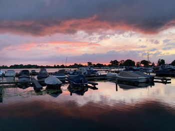 Sailboats moored at harbor against sky during sunset