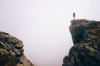 Low angle view of man on rock against sky