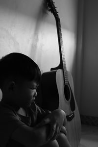 Rear view of boy playing guitar