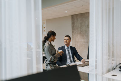 Smiling businessman and businesswoman talking in office