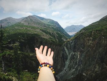 Midsection of person hand on mountain against sky