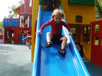 Full length of cute girl playing on slide at playground
