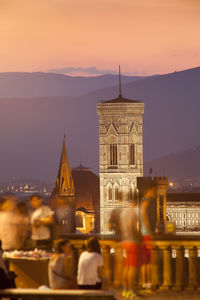Illuminated city against sky at sunset