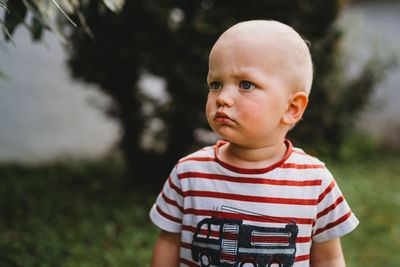 Portrait of beautiful boy with serious face looking to side outside