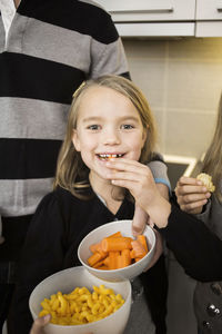 Portrait of little girl eating carrot at home