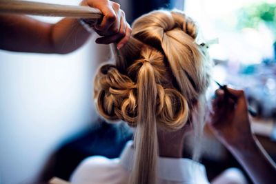 Cropped hands of hairdresser and beautician preparing bride for wedding