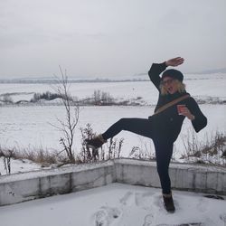 Portrait of young woman standing on snow covered shore