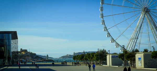 People in amusement park against blue sky