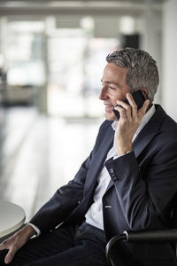 Mature businessman using mobile phone while sitting in office