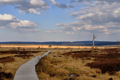 Empty road on field against sky