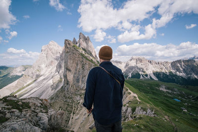 Rear view of man looking at mountains against sky