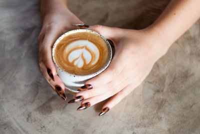 Midsection of woman holding coffee cup on table