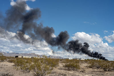 Smoke over landscape against sky