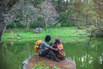 People sitting by lake in forest