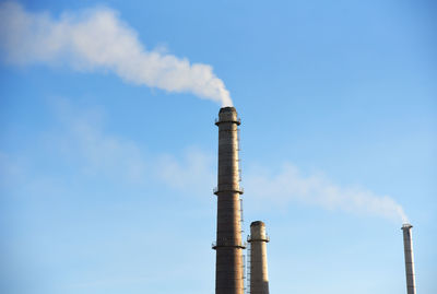 Low angle view of smoke emitting from chimney against sky