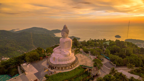 Statue by temple against sky during sunset