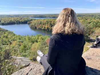 Rear view of woman looking at waterfall against sky