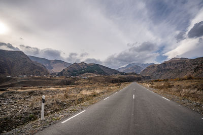 Road by mountains against sky