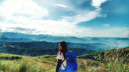 Rear view of woman standing on mountain against sky