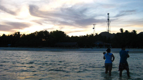 People on lake against sky during winter