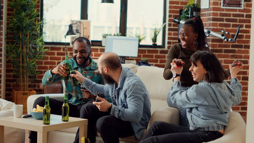 Side view of friends using mobile phone while sitting on table