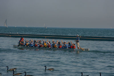 Group of people on boat in sea against sky