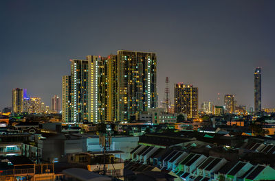 Illuminated modern buildings against sky at night