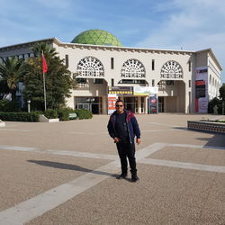 Full length portrait of man standing against building in city