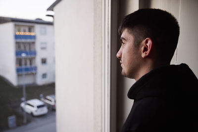 Thoughtful young man looking through window