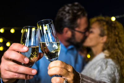 Couple kissing while holding champagne outdoors