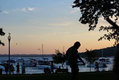 Silhouette person on shore against sky during sunset