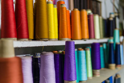 Close-up of multi colored spools on shelves at shop