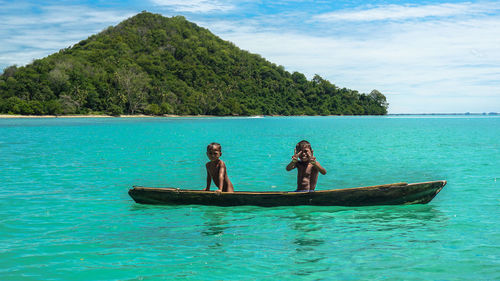 People in boat sailing on sea against blue sky