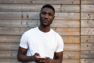 Young man looking away while standing on wood