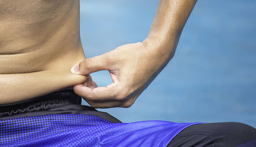 Midsection of shirtless man touching stomach