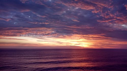 Scenic view of sea against dramatic sky during sunset