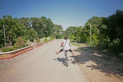 Rear view of person riding bicycle on road