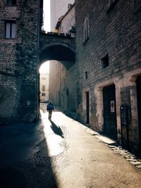 Man walking in alley amidst buildings in city