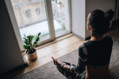 High angle view of woman sitting by window at home